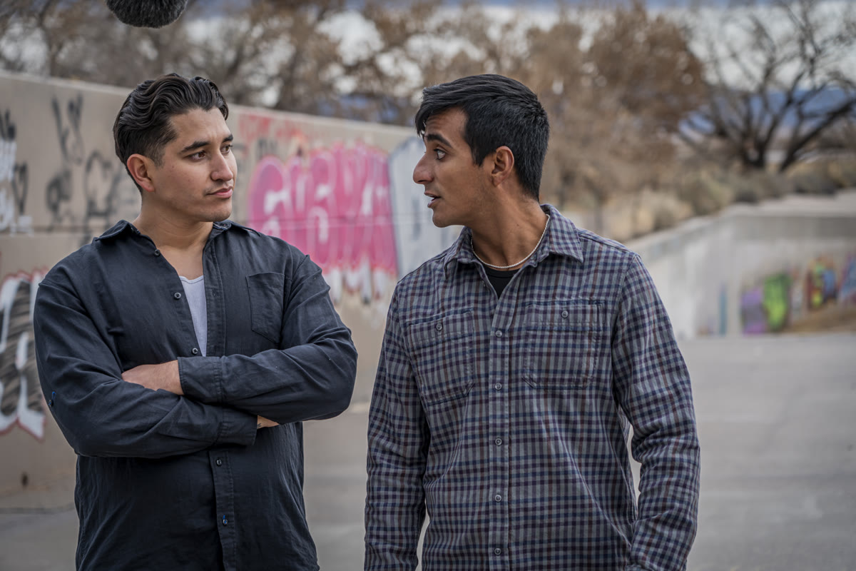 Still from Fresh Starts: two young men talk in front of a graffiti wall